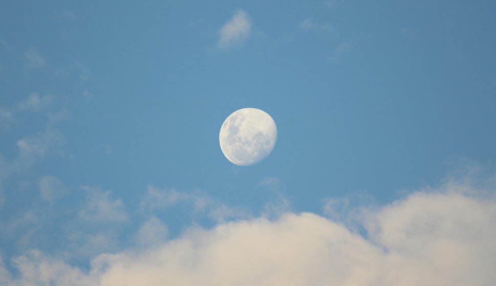 Fullmåne på en blå himmel med moln